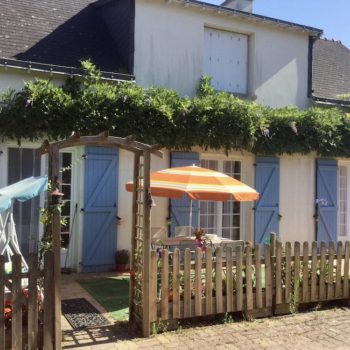 Façade de maison aux volets bleus sous le soleil avec une glycine